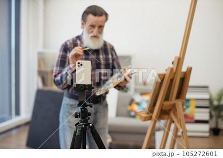 Senior painter making video recording on white smartphone Senior painter making video recording on white smartphone 105272601
