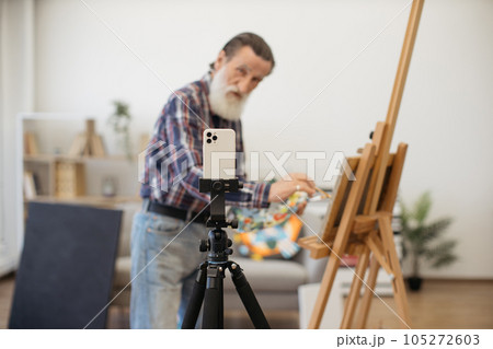 Senior painter making video recording on white smartphone Senior painter making video recording on white smartphone 105272603