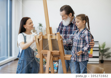Creative family drawing on paper at easel in home studio 105272882