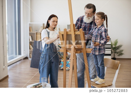 Creative family drawing on paper at easel in home studio Creative family drawing on paper at easel in home studio 105272883