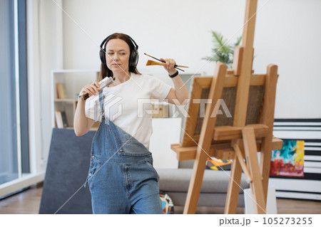 Lady with brush moving to beat of song via headphones 105273255