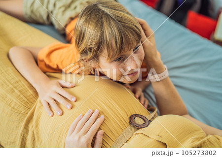Young pregnant mother hugging her little boy lying in bed at night. Caring and loving parent hugging child Young pregnant mother hugging her little boy lying in bed at night. Caring and loving parent hugging child 105273802