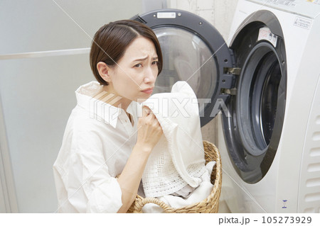 洗濯機の前で洗濯物の匂いに悩むミドルエイジの女性 105273929