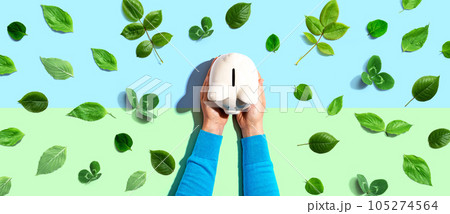 Person holding a piggy bank with green leaves 105274564