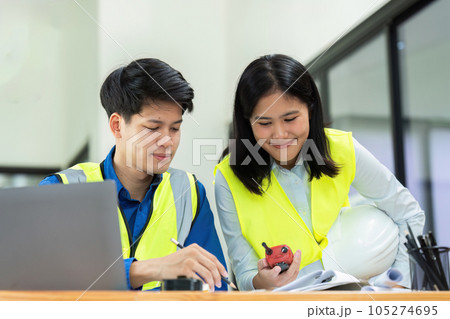 Civil engineers and architects discuss project construction together at office and holding walkie talkie Civil engineers and architects discuss project construction together at office and holding walkie talkie 105274695