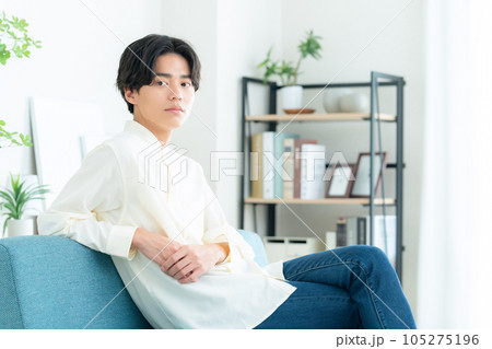 リビングでソファに座ってくつろぐ若い男性 105275196