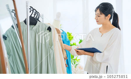 タブレットを見ながら商品をチェックするアパレル店員 タブレットを見ながら商品をチェックするアパレル店員 105275851