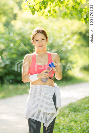 a young woman wearing summer morning sportswear and carrying a water bottle a young woman wearing summer morning sportswear and carrying a water bottle 105276133