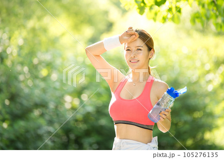 a young woman wearing summer morning sportswear and carrying a water bottle 105276135