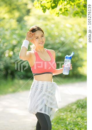 a young woman wearing summer morning sportswear and carrying a water bottle a young woman wearing summer morning sportswear and carrying a water bottle 105276139