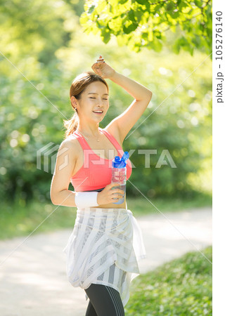 a young woman wearing summer morning sportswear and carrying a water bottle 105276140