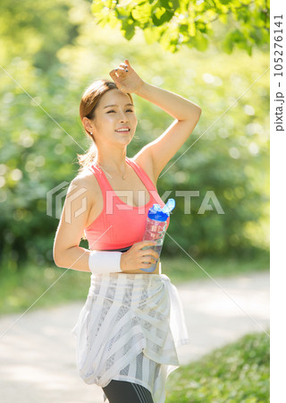 a young woman wearing summer morning sportswear and carrying a water bottle a young woman wearing summer morning sportswear and carrying a water bottle 105276141