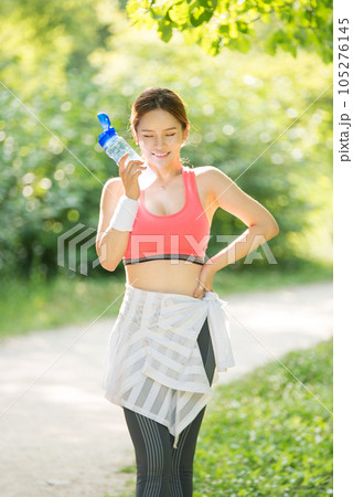 a young woman wearing summer morning sportswear and carrying a water bottle a young woman wearing summer morning sportswear and carrying a water bottle 105276145