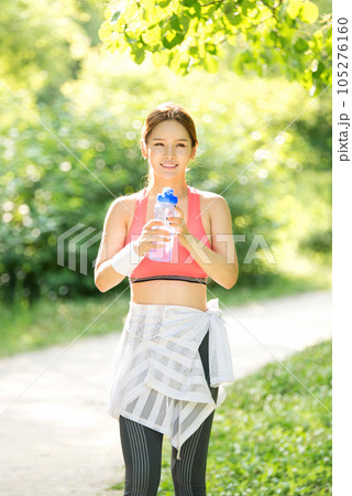 a young woman wearing summer morning sportswear and carrying a water bottle 105276160