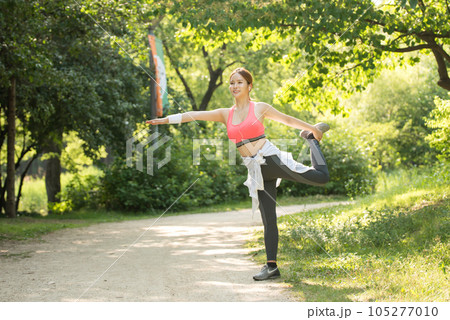 a beautiful young woman exercising in the park on a summer morning a beautiful young woman exercising in the park on a summer morning 105277010