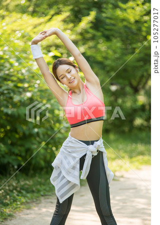 a beautiful young woman exercising in the park on a summer morning 105277017