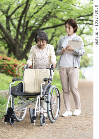 公園で散歩をするシニア女性と介護士 105278050