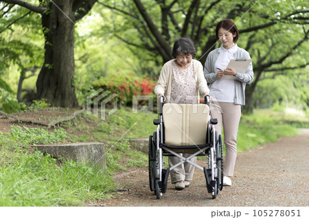 公園で散歩をするシニア女性と介護士 105278051