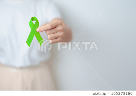 Woman holding green Ribbon for world Lymphoma Awareness September month, world Mental Health Day, Liver, Gallbladders, bile duct, cervical, kidney Cancer. Healthcare and world cancer day concept 105278160