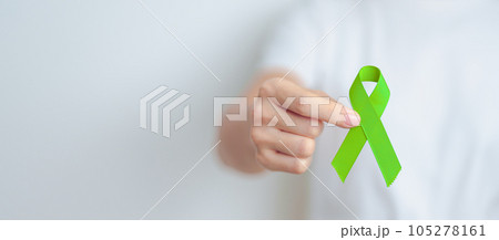 Woman holding green Ribbon for world Lymphoma Awareness September month, world Mental Health Day, Liver, Gallbladders, bile duct, cervical, kidney Cancer. Healthcare and world cancer day concept 105278161