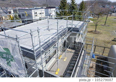 住宅リフォーム 外壁塗装と屋根の張替え作業中の家（空撮） 105279087