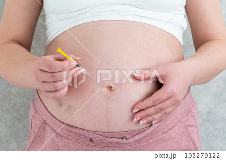 Pregnant woman making injection in stomach 105279122
