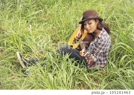 Young women playing acoustic guitar outdoor in green park. Woman person playing acoustic guitar music instrument at home, young Asian musician girl lifestyle in beautiful nature. Happy guitarist 105281463
