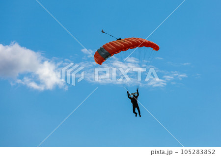 Parachute in the sky. Skydiver is flying a parachute in the blue sky Parachute in the sky. Skydiver is flying a parachute in the blue sky 105283852