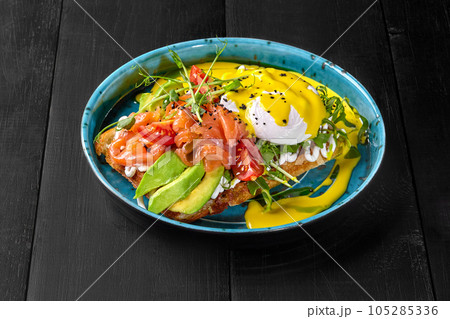 Belgian waffle with avocado, salmon, poached egg, tomatoes, greens and cheese sauce Belgian waffle with avocado, salmon, poached egg, tomatoes, greens and cheese sauce 105285336