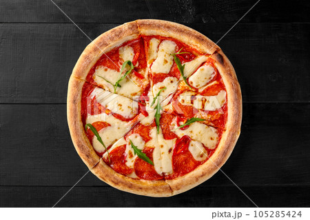 Spicy pepperoni pizza with sausage, tomato sauce, mozzarella and arugula Spicy pepperoni pizza with sausage, tomato sauce, mozzarella and arugula 105285424