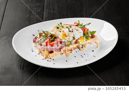 Belgian waffle with ham, cheese, chili pepper, poached egg and fresh arugula 105285453