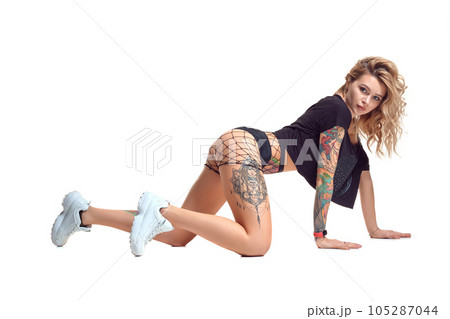 Sexy blond twerk woman with tattoed body and long curly hair is posing in studio. 105287044