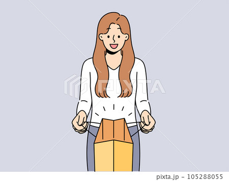 Woman holds paper bag and looks at screen showing off successful shopping and buying goods 105288055