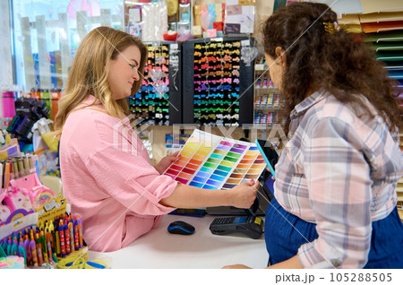 Saleswoman demonstrating a palette with color swatches of watercolor paints to customer shopping in a stationery store 105288505