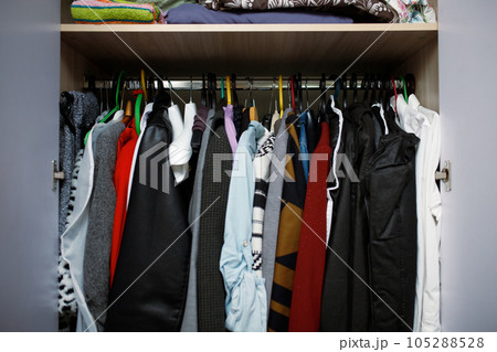 Open closet with a variety of clothes hanging randomly on hangers 105288528