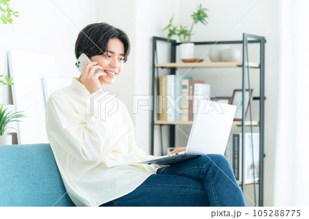 リビングでソファに座ってパソコンを操作する若い男性 105288775