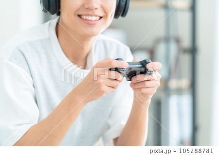 リビングでソファに座ってヘッドホンをつけてゲームをする若い男性 リビングでソファに座ってヘッドホンをつけてゲームをする若い男性 105288781