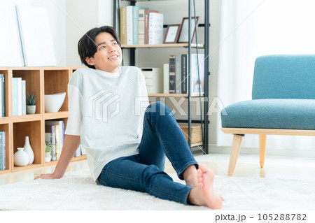 リビングでラグに座ってくつろぐ若い男性 リビングでラグに座ってくつろぐ若い男性 105288782