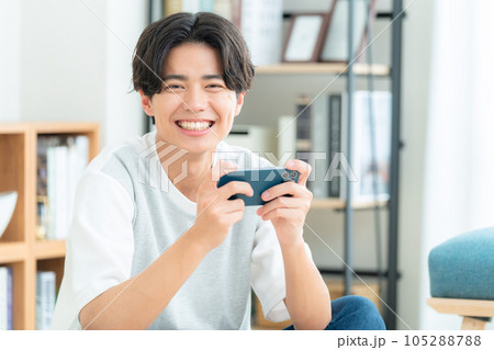 リビングでラグに座ってスマホを操作する若い男性 リビングでラグに座ってスマホを操作する若い男性 105288788