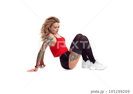 Sexy blond twerk woman with tattoed body and long curly hair is posing in studio. 105289209