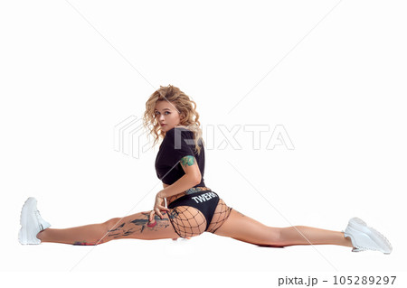 Sexy blond twerk woman with tattoed body and long curly hair is posing in studio. Sexy blond twerk woman with tattoed body and long curly hair is posing in studio. 105289297