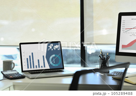 Laptop computer with statistics, marketing research results or statistics data on screen and calculator on white office desk 105289488
