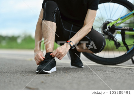 Male cyclist in sportswear tying shoelaces, getting ready for riding. Active sporty, people and healthy lifestyle concept 105289491