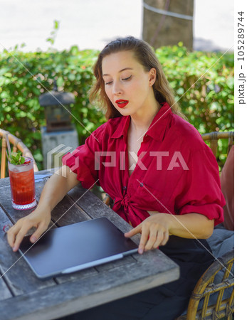 Beautiful blonde woman preparing her electronical tablet for a remote work and interview as a freelancer in a garden Beautiful blonde woman preparing her electronical tablet for a remote work and interview as a freelancer in a garden 105289744