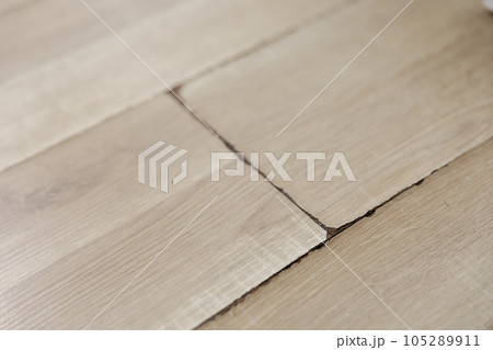 Swollen and dirty laminate floor, close up view. Moisture damage. Laminate flooring has swelled. Damaged laminate planks. Home, property insurance. 105289911