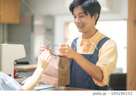 商品をお渡しする笑顔の飲食店の店員 105290152