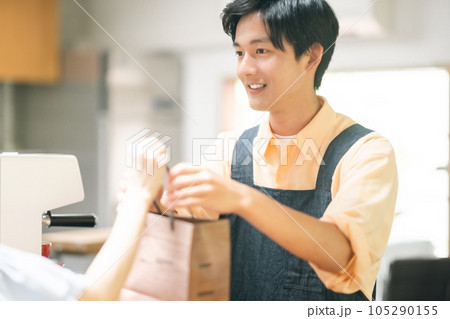 商品をお渡しする笑顔の飲食店の店員 105290155