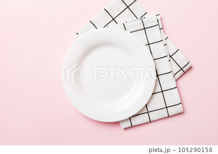 Top view on colored background empty round white plate on tablecloth for food. Empty dish on napkin with space for your design Top view on colored background empty round white plate on tablecloth for food. Empty dish on napkin with space for your design 105290158