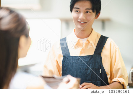 商品をお渡しする笑顔の飲食店の店員 105290161