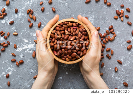 Woman hands holding a wooden bowl with peanuts. Healthy food and snack. Vegetarian snacks of different nuts Woman hands holding a wooden bowl with peanuts. Healthy food and snack. Vegetarian snacks of different nuts 105290329